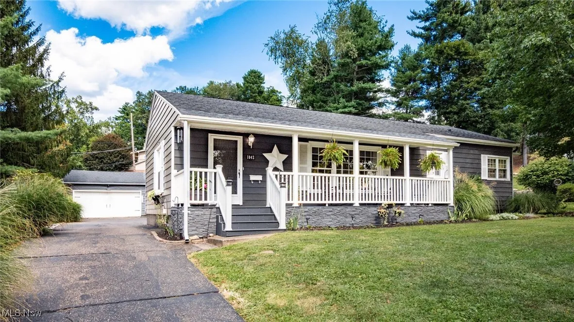 View of front facade with a porch, an outdoor structure, a front yard, and a garage