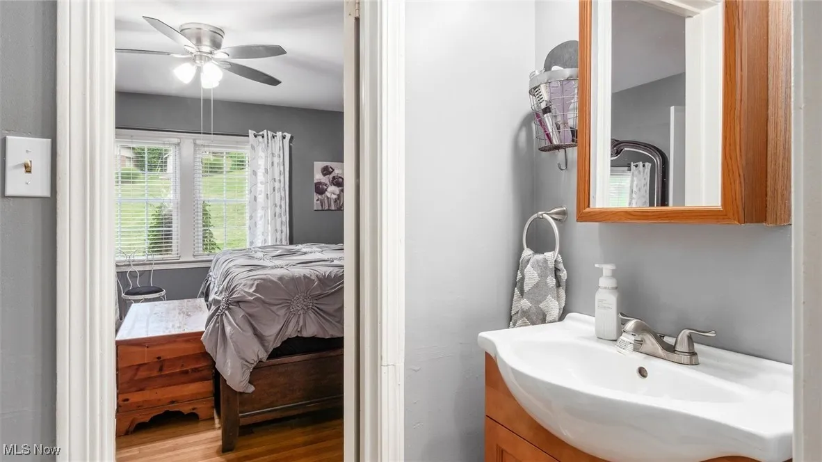 Bathroom with vanity, wood finished floors, a ceiling fan, and ensuite bath