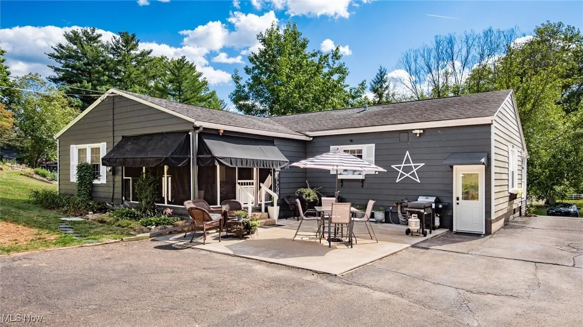 Rear view of property featuring a shingled roof and a patio