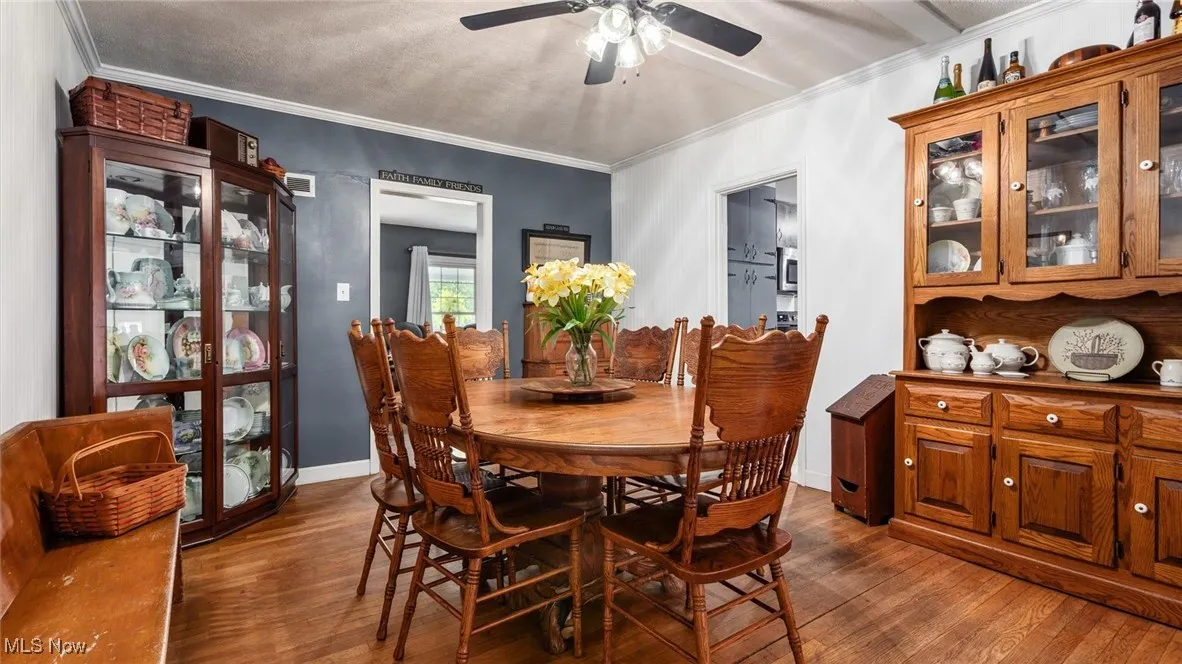 Dining space featuring ornamental molding, dark wood-style flooring, a ceiling fan, and a textured ceiling