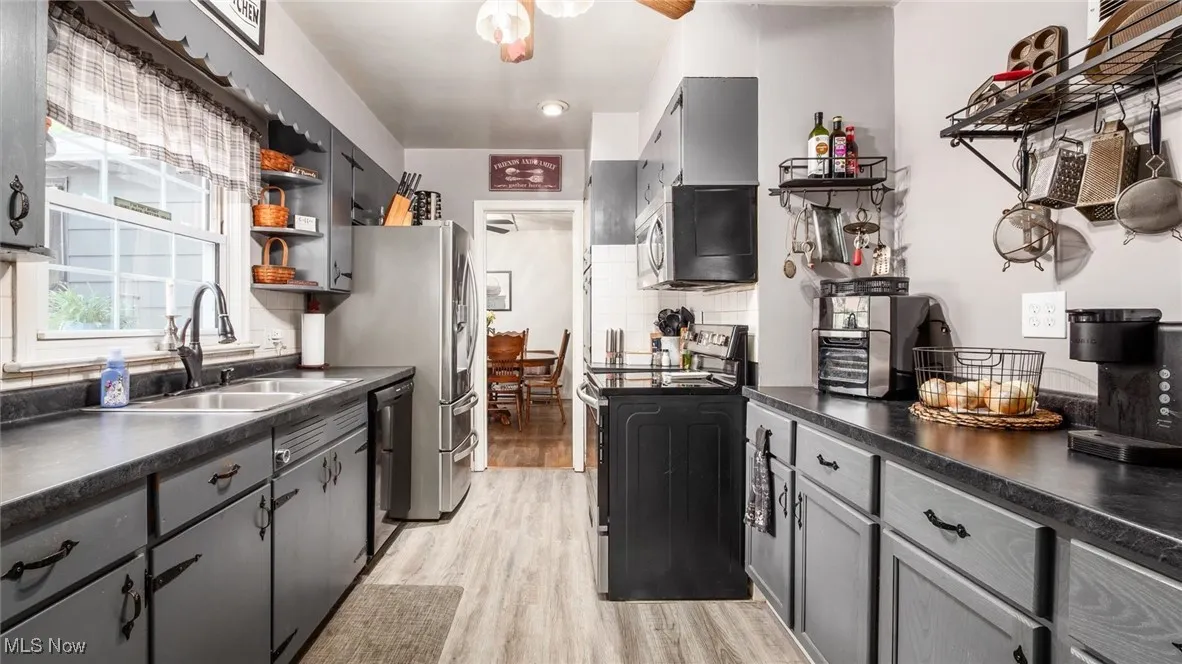 Kitchen featuring dark countertops, open shelves, gray cabinetry, and range with electric stovetop