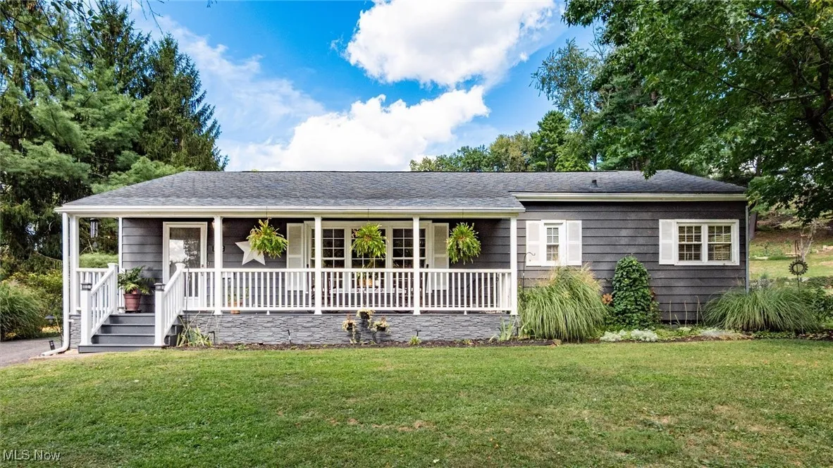 Ranch-style home featuring a front lawn, covered porch, and a shingled roof