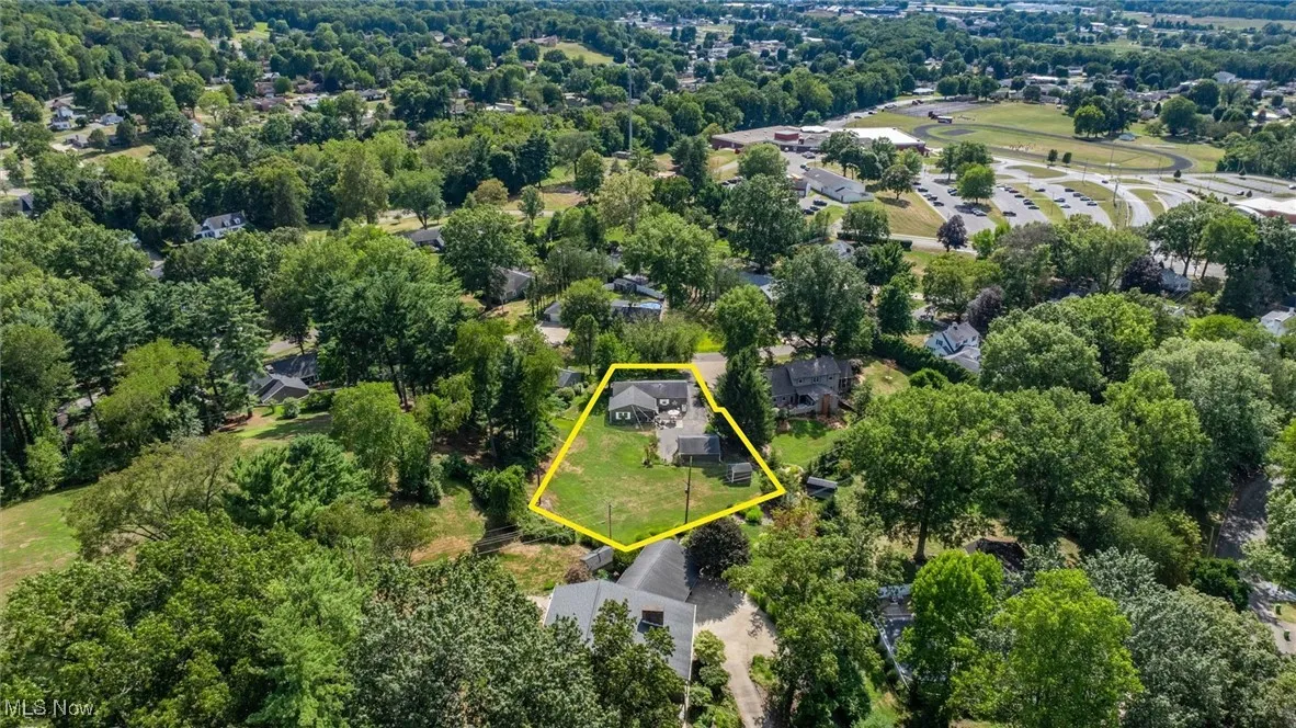 Aerial view of property and surrounding area featuring property boundaries highlighted and a tree filled landscape