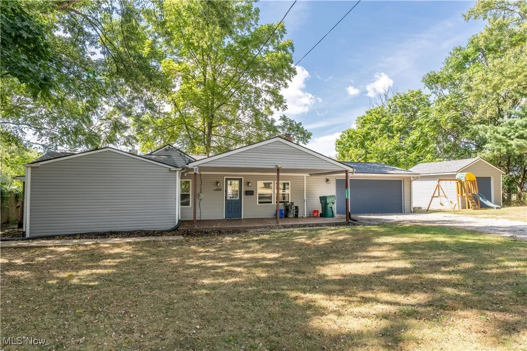 Ranch-style home with a front yard, covered porch, an outdoor structure, and driveway