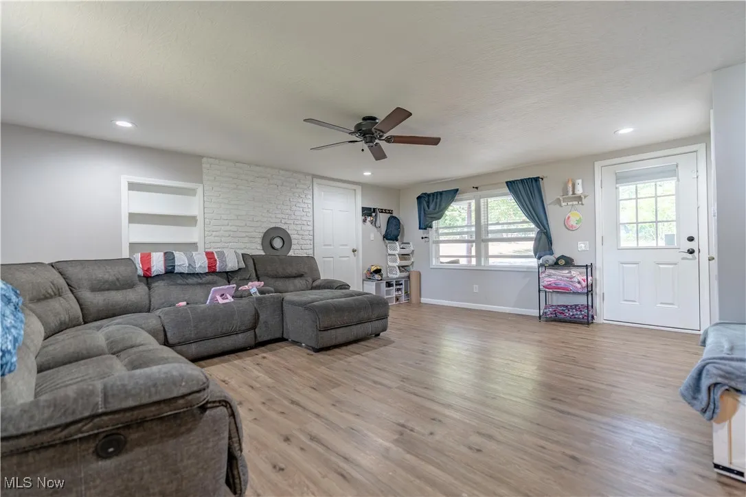 Living room with light wood finished floors, a ceiling fan, and recessed lighting