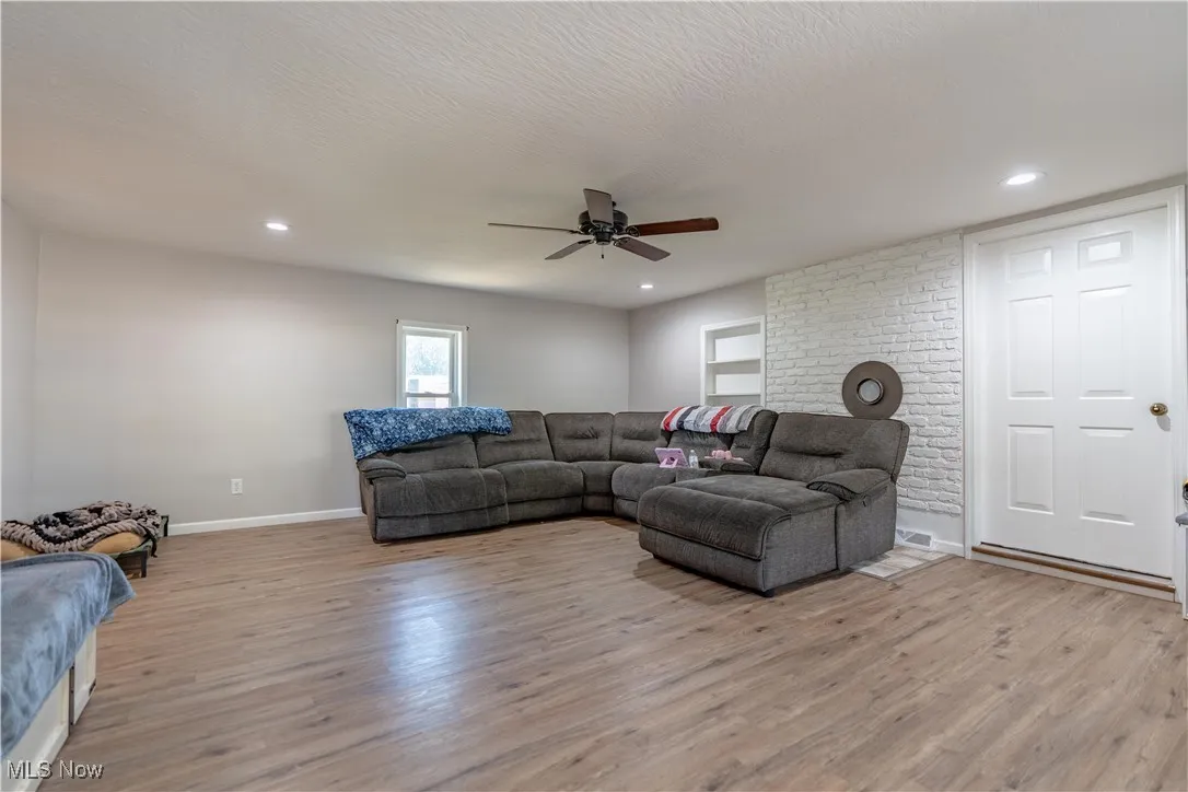Living room with light wood finished floors, a ceiling fan, a textured ceiling, and recessed lighting
