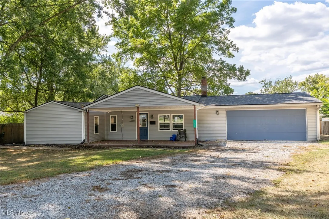 Ranch-style house featuring driveway, a garage, covered porch, and a chimney