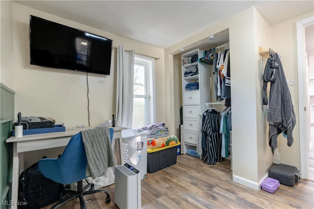 Bedroom featuring wood finished floors, a closet, and a desk