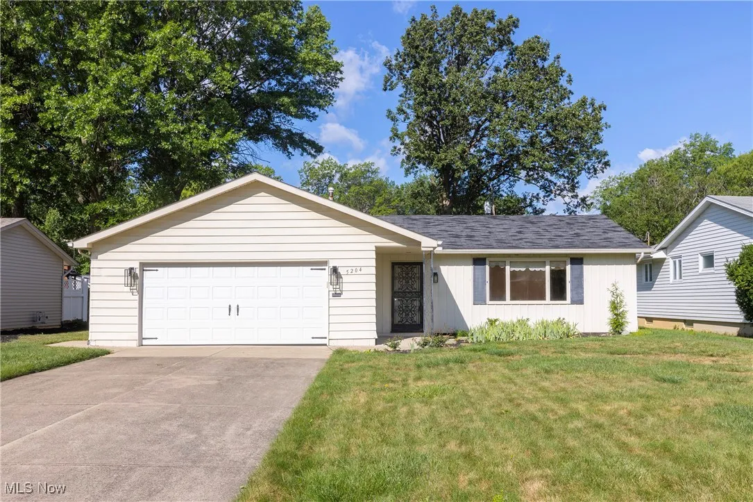 Ranch-style house featuring a front yard, board and batten siding, concrete driveway, and a garage