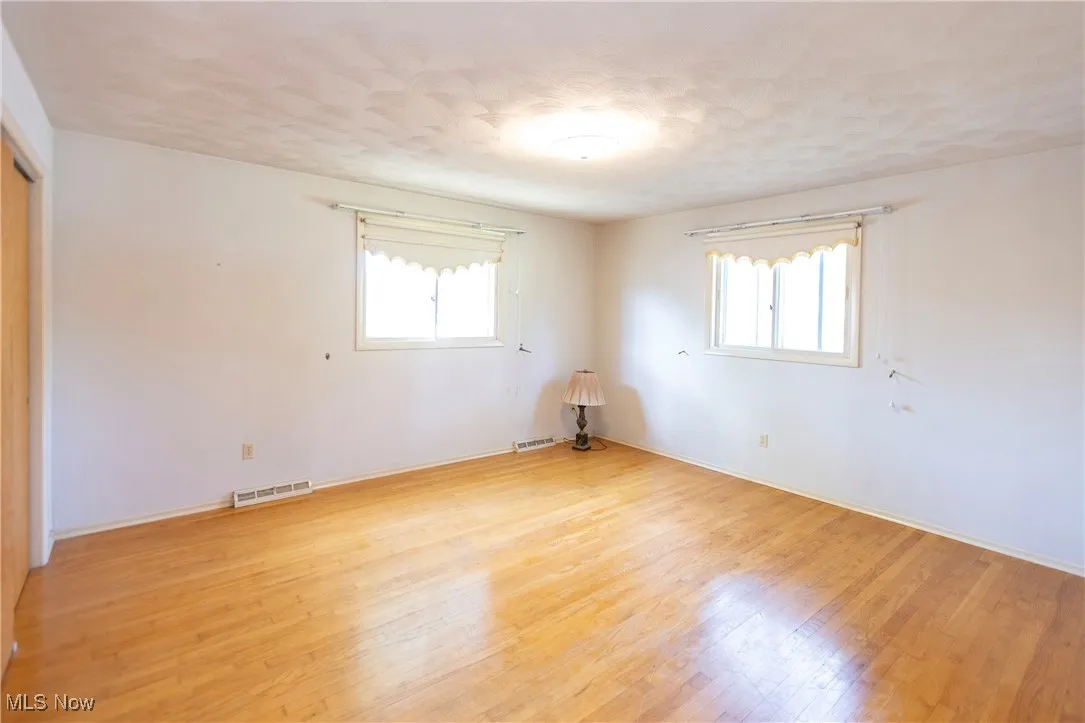 Empty room with plenty of natural light, light wood finished floors, and a textured ceiling