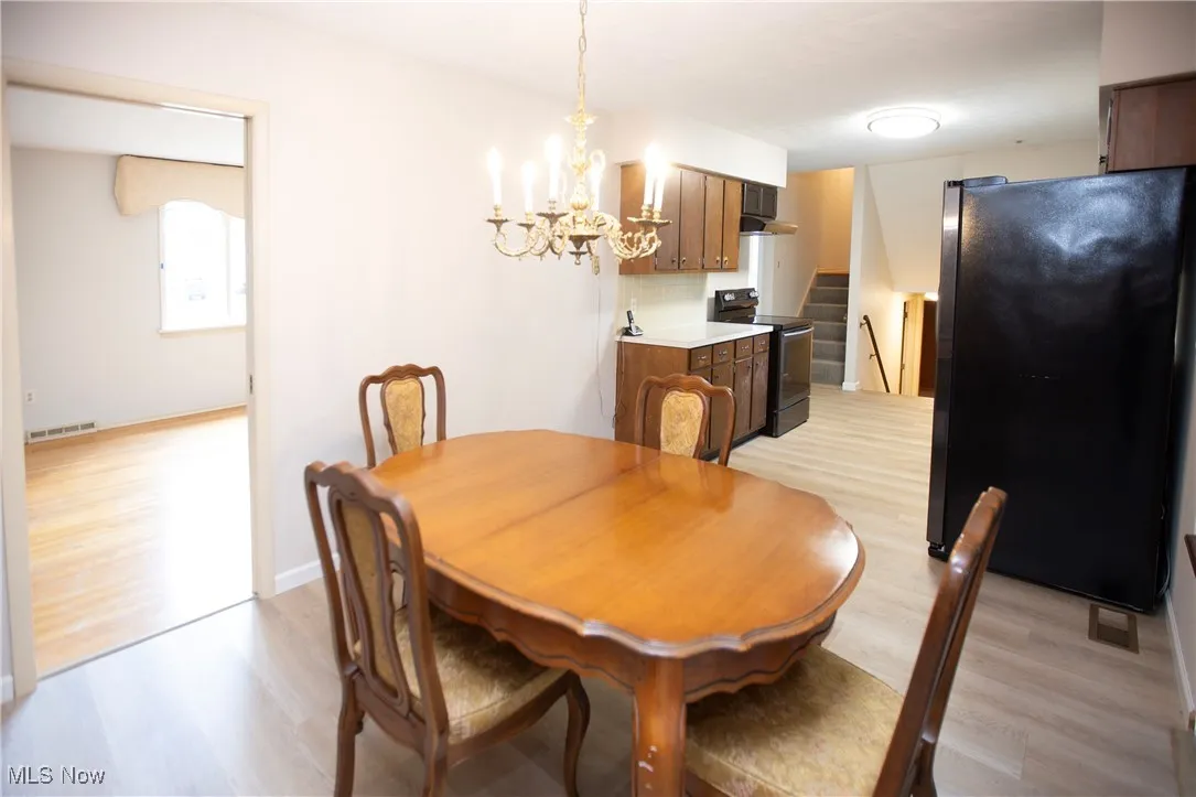 Dining room featuring light wood-type flooring, a chandelier, and stairs