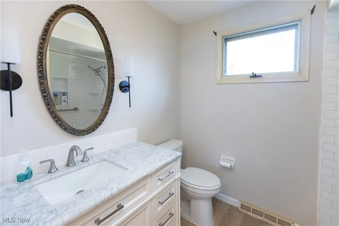 Full bathroom featuring vanity, light wood-style floors, and a tile shower