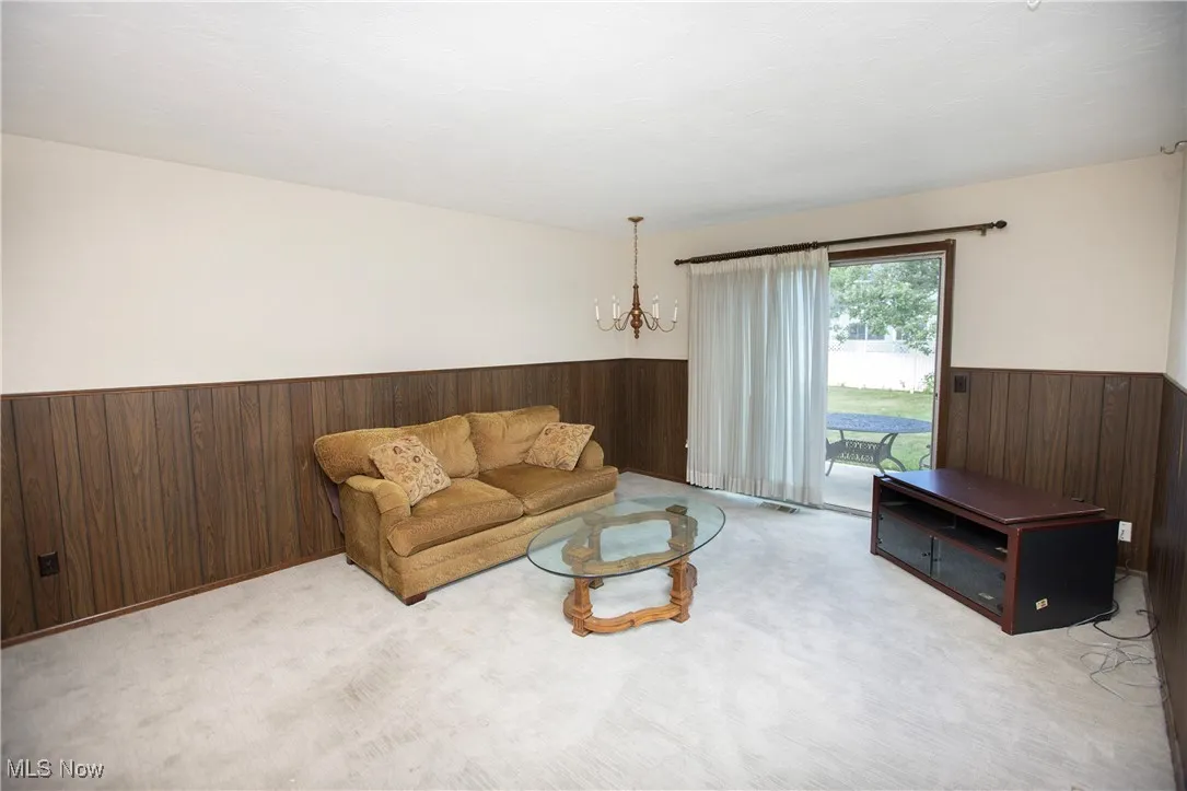 Living area with wooden walls, wainscoting, a chandelier, and carpet