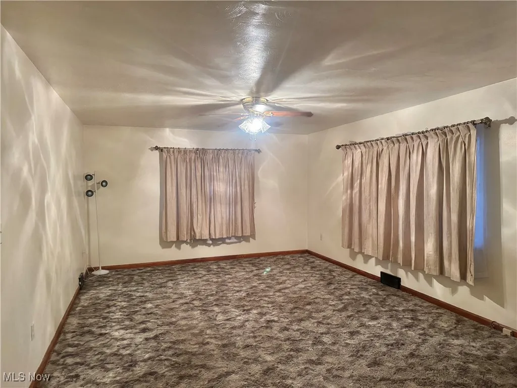 Spare room featuring carpet and ceiling fan