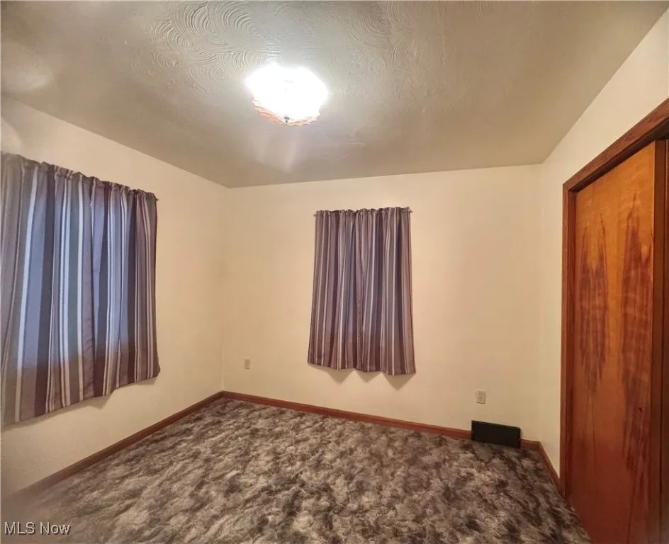 Unfurnished bedroom with a textured ceiling, carpet flooring, and a closet