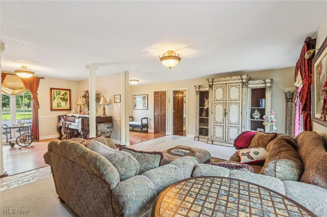 Carpeted living room with ornate columns and wood finished floors