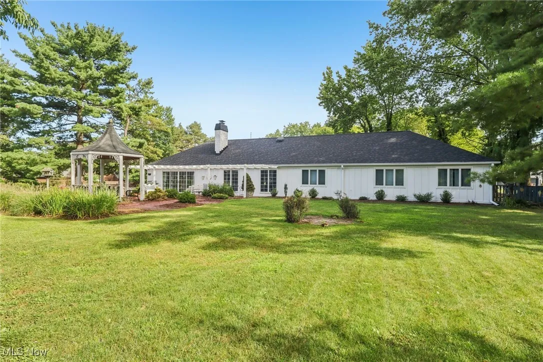 Back of property with a gazebo, a yard, a chimney, and a patio