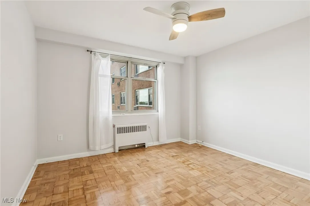 Unfurnished room featuring radiator heating unit and ceiling fan