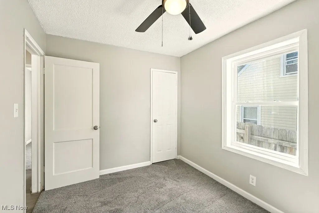 Unfurnished bedroom with carpet flooring, a textured ceiling, and a ceiling fan