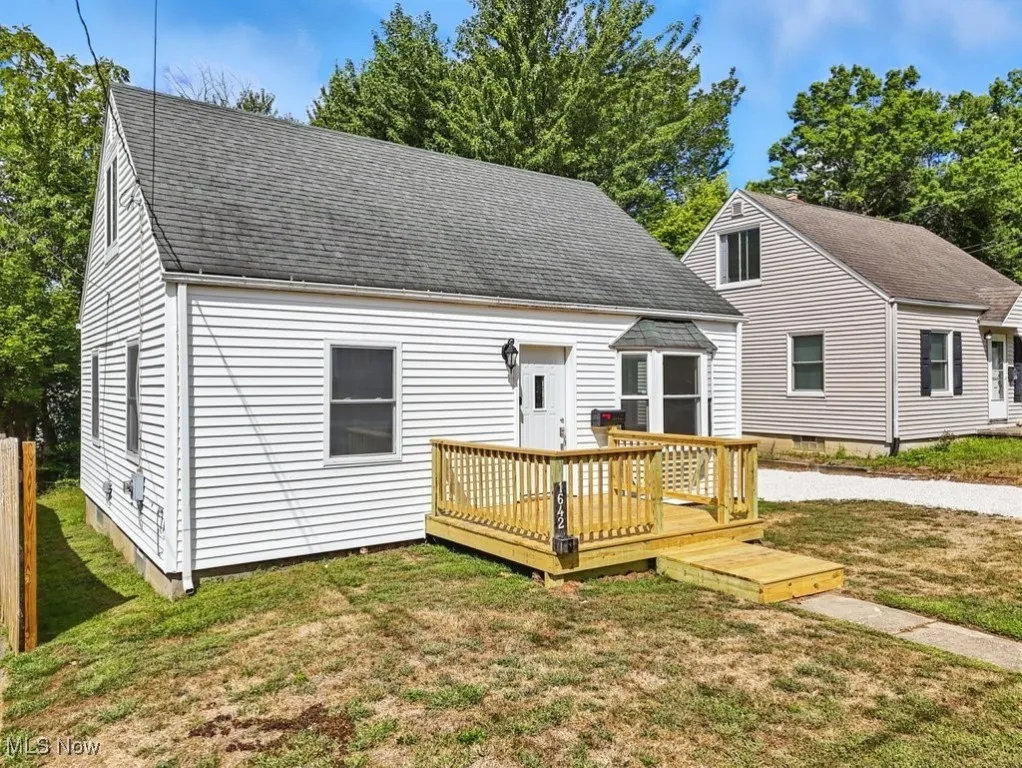 View of front of house featuring a deck, a front lawn, and a shingled roof