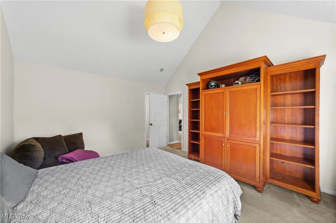 Bedroom with light carpet and high vaulted ceiling
