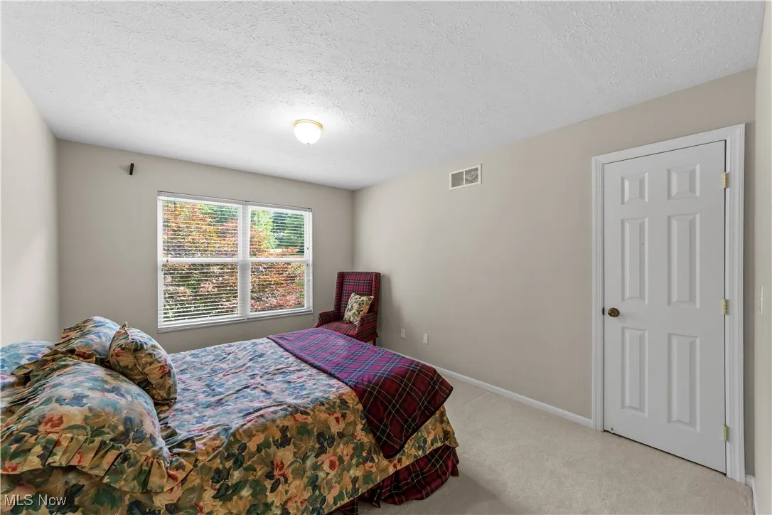Carpeted bedroom featuring a textured ceiling and baseboards
