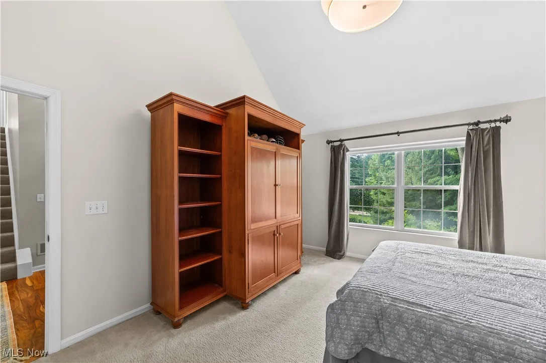 Bedroom with light carpet and high vaulted ceiling