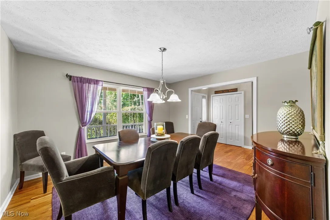 Dining space with a textured ceiling, light wood finished floors, and a chandelier