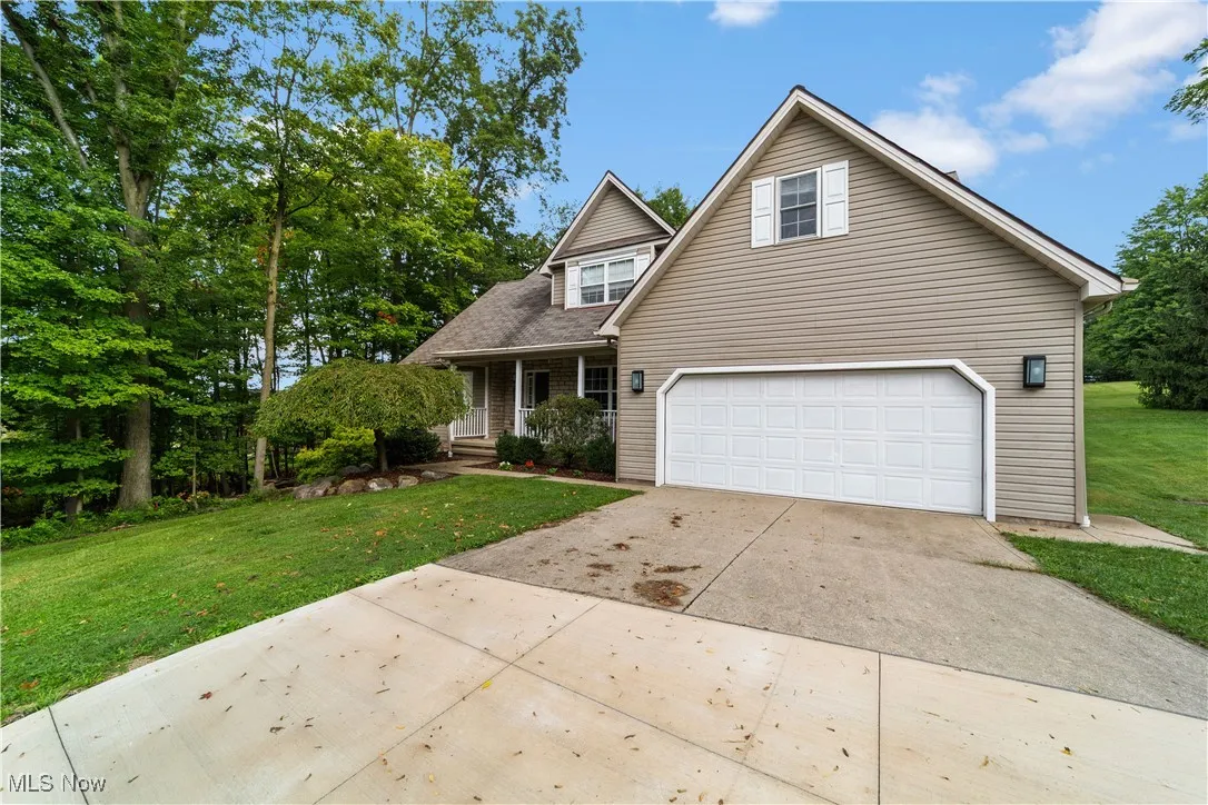Traditional home featuring a porch, driveway, a front yard, and a garage