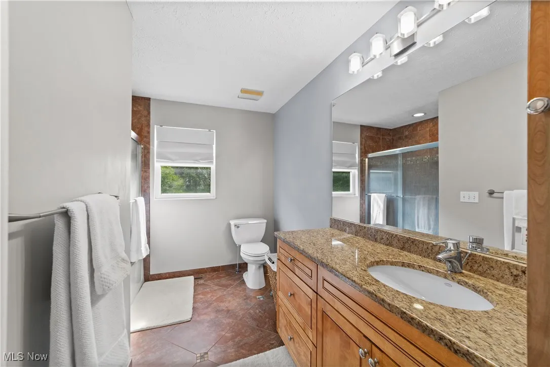 Bathroom with vanity, a shower stall, a textured ceiling, and dark tile patterned flooring