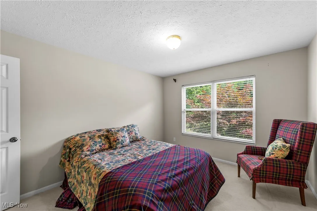 Bedroom featuring light colored carpet and a textured ceiling