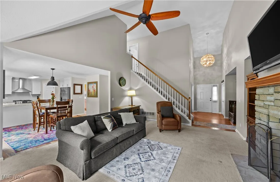 Living room featuring a towering ceiling, a fireplace, carpet, a chandelier, and stairs