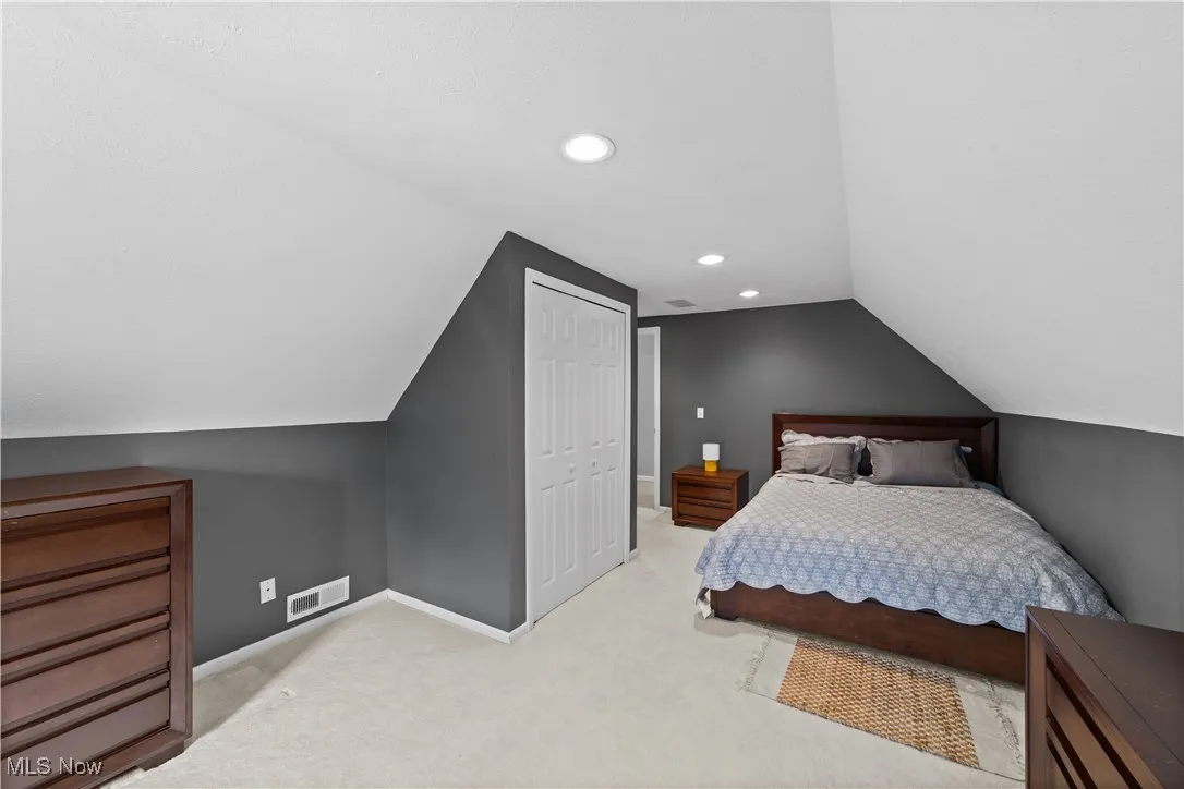 Carpeted bedroom with recessed lighting, vaulted ceiling, and a closet