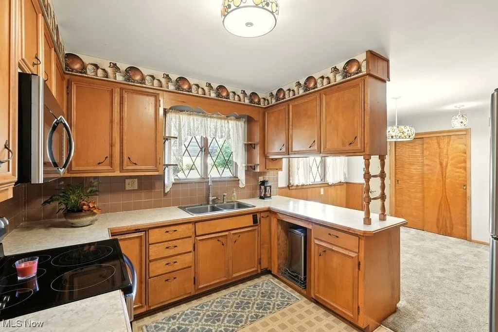 Kitchen with appliances with stainless steel finishes, light countertops, tasteful backsplash, and brown cabinetry