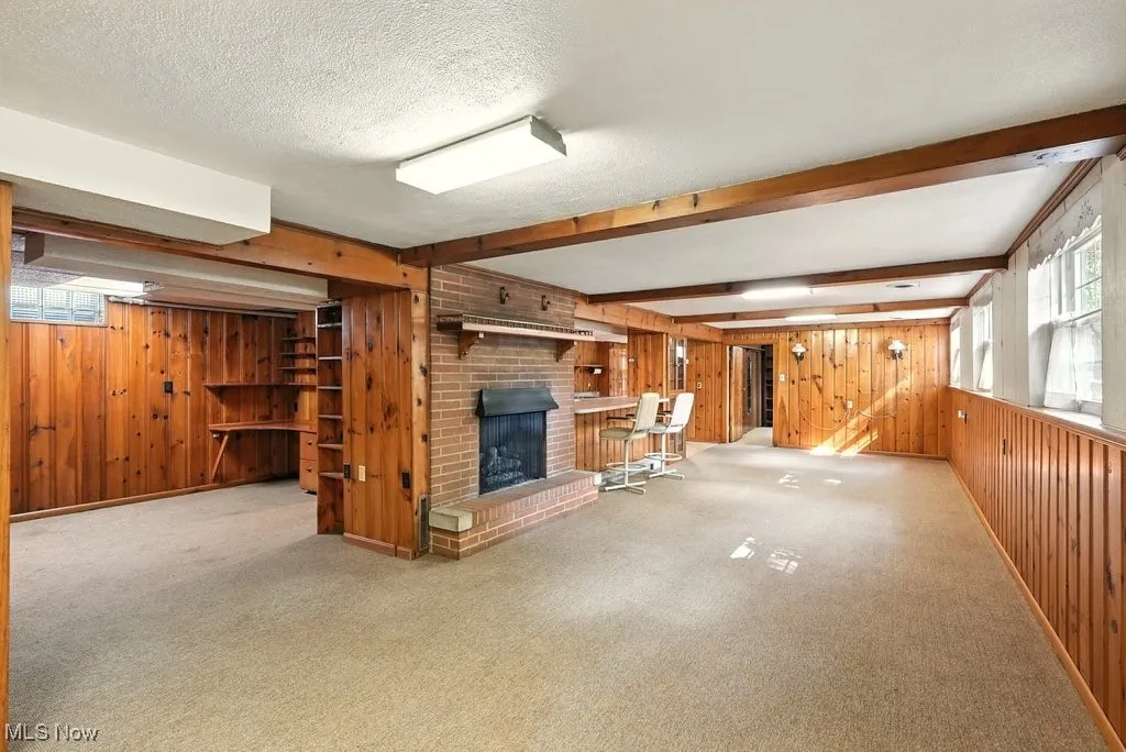 Basement with wooden walls, a fireplace, carpet, and a textured ceiling