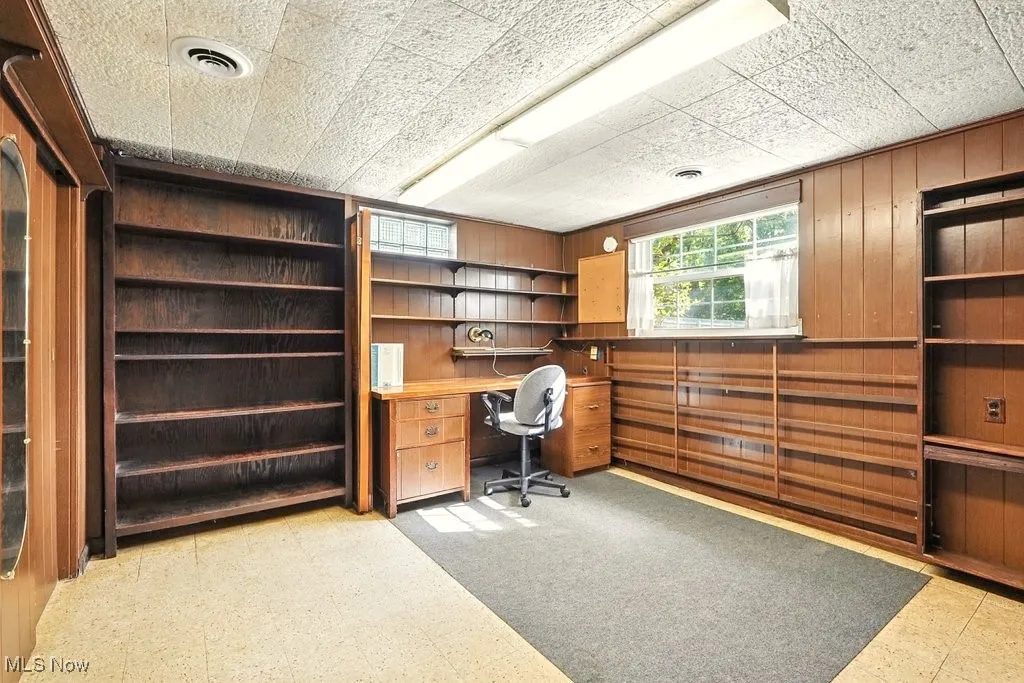 Home office featuring light flooring and wooden walls