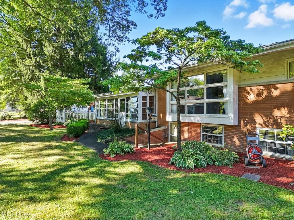 Back of house with brick siding, a sunroom, and a lawn