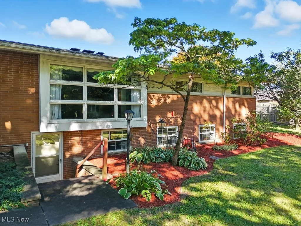 Back of property featuring brick siding and a lawn