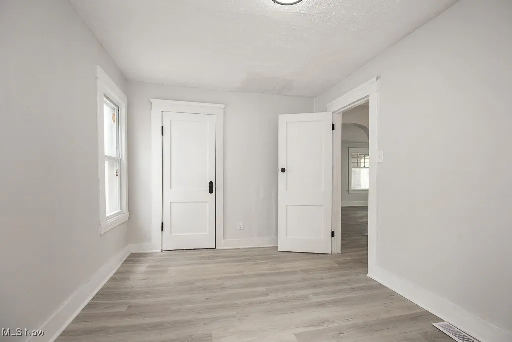 Unfurnished bedroom with light wood-style flooring, a textured ceiling, and a closet