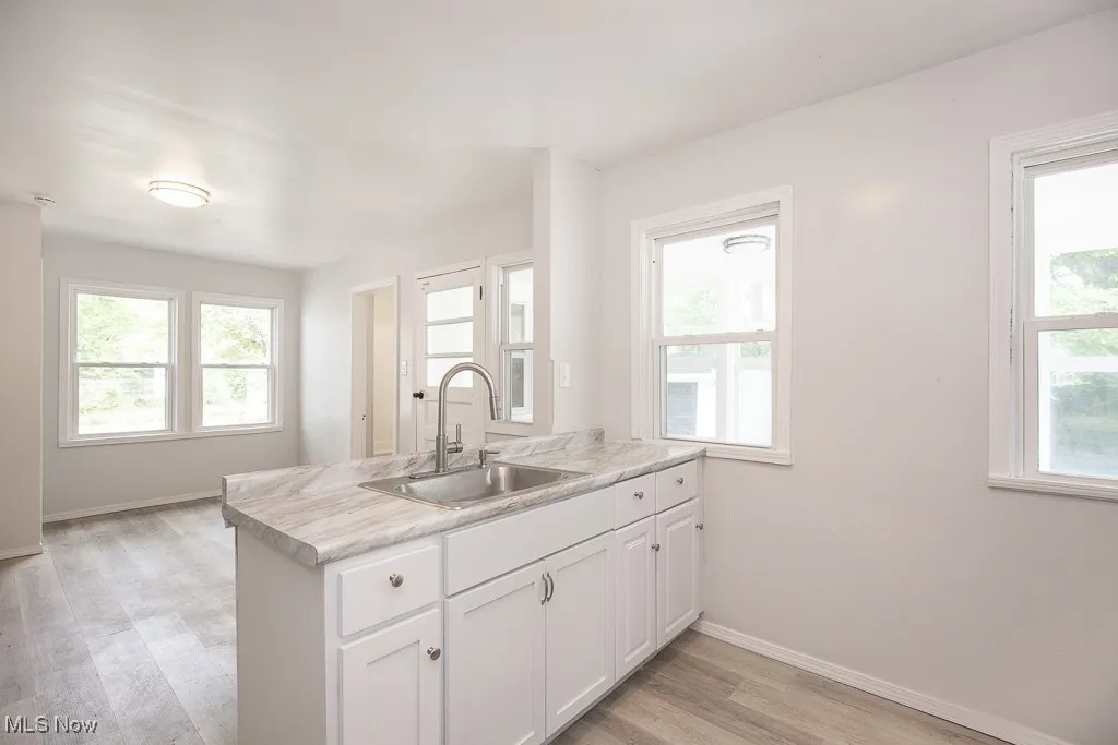 Kitchen with white cabinetry, light countertops, a peninsula, light wood-type flooring, and plenty of natural light