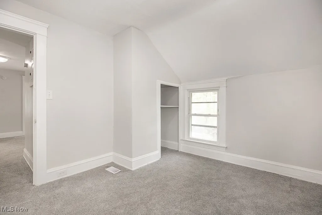 Unfurnished bedroom featuring lofted ceiling and carpet floors