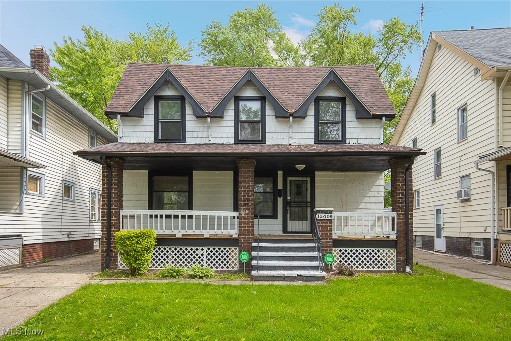 View of front of property with a shingled roof, a front yard, and covered porch