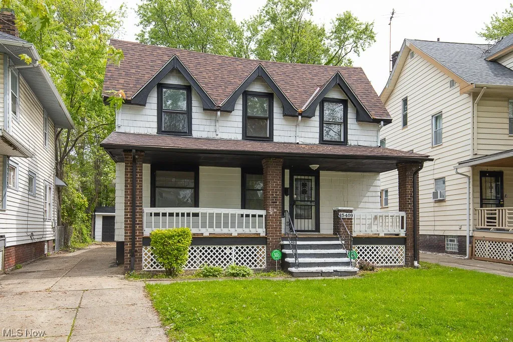 View of front of property featuring roof with shingles, a front yard, a porch, and an outbuilding