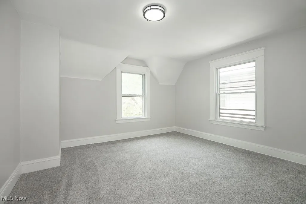 Additional living space with light carpet and lofted ceiling
