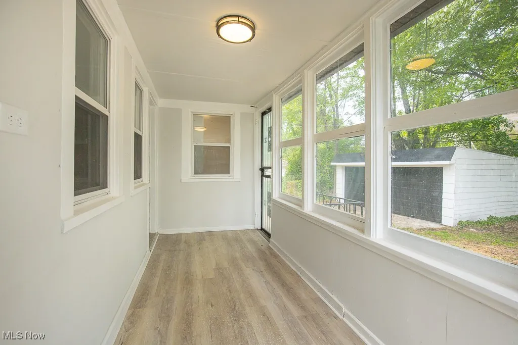 Unfurnished sunroom featuring wood finished floors and baseboards