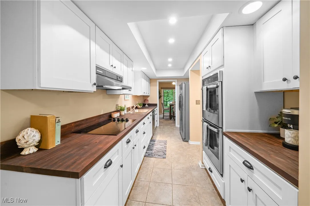 updated kitchen with newer white cabinets, newer stainless steal appliances and butchers block counter tops.
