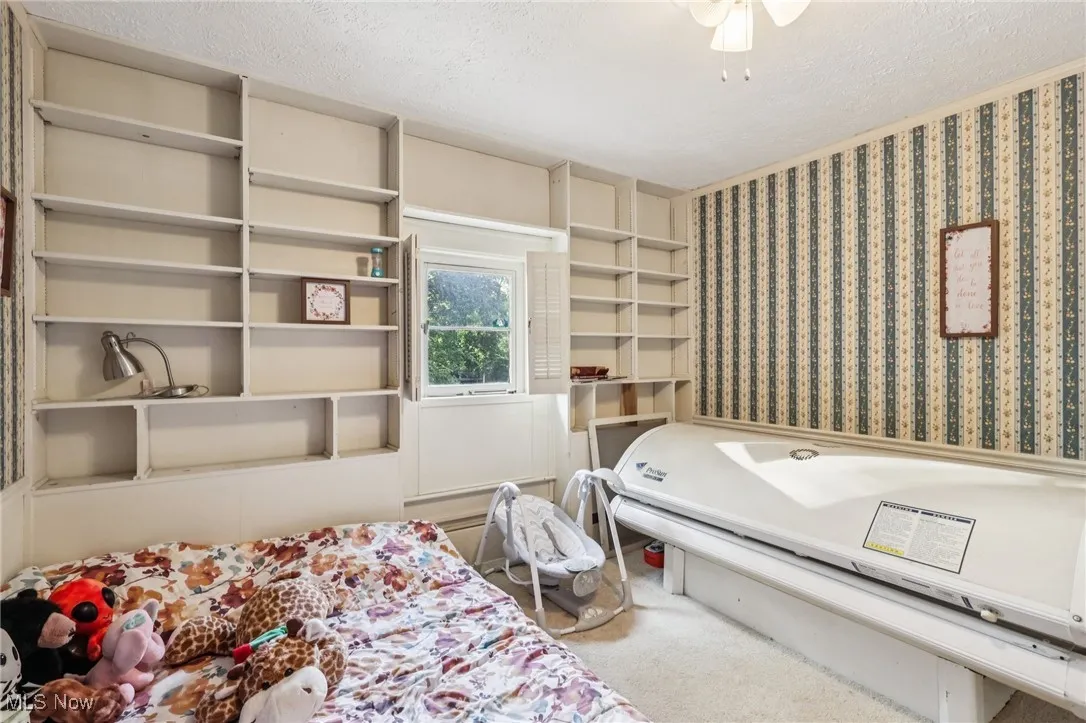 Bedroom featuring a textured ceiling, carpet, and wallpapered walls