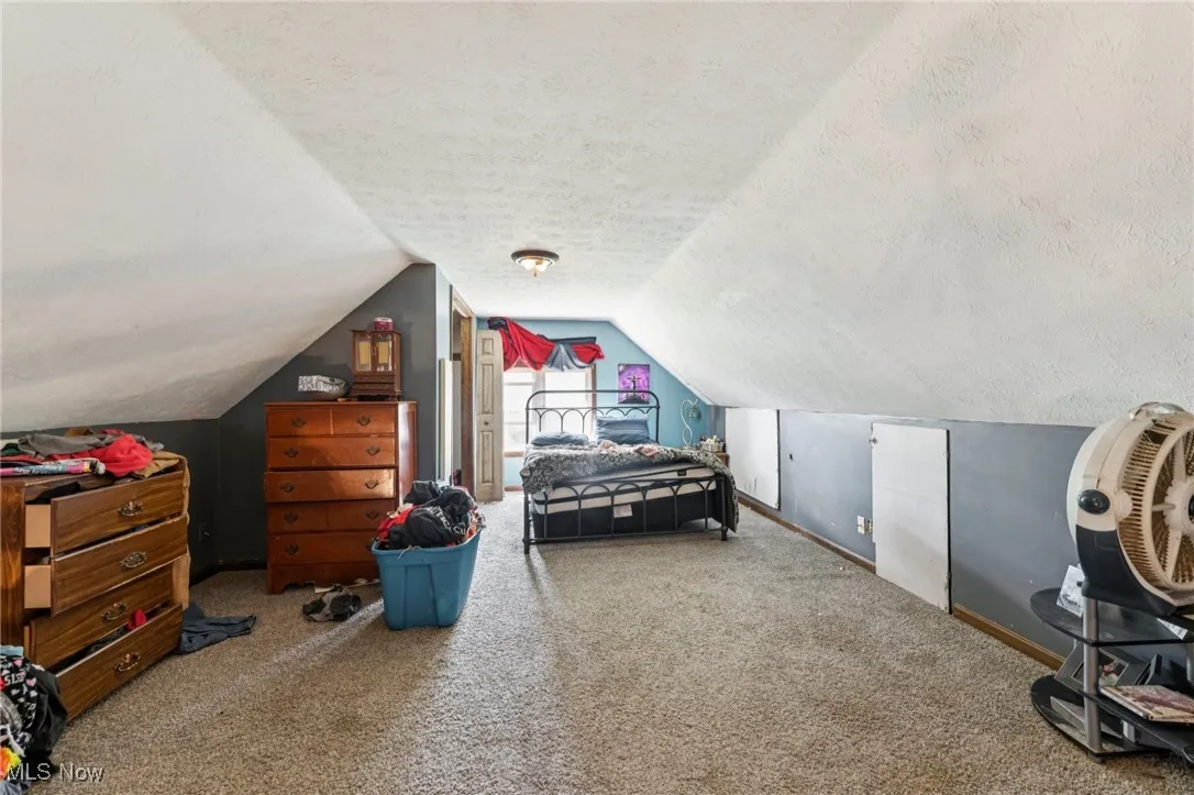 Bedroom with a textured ceiling, carpet, and vaulted ceiling