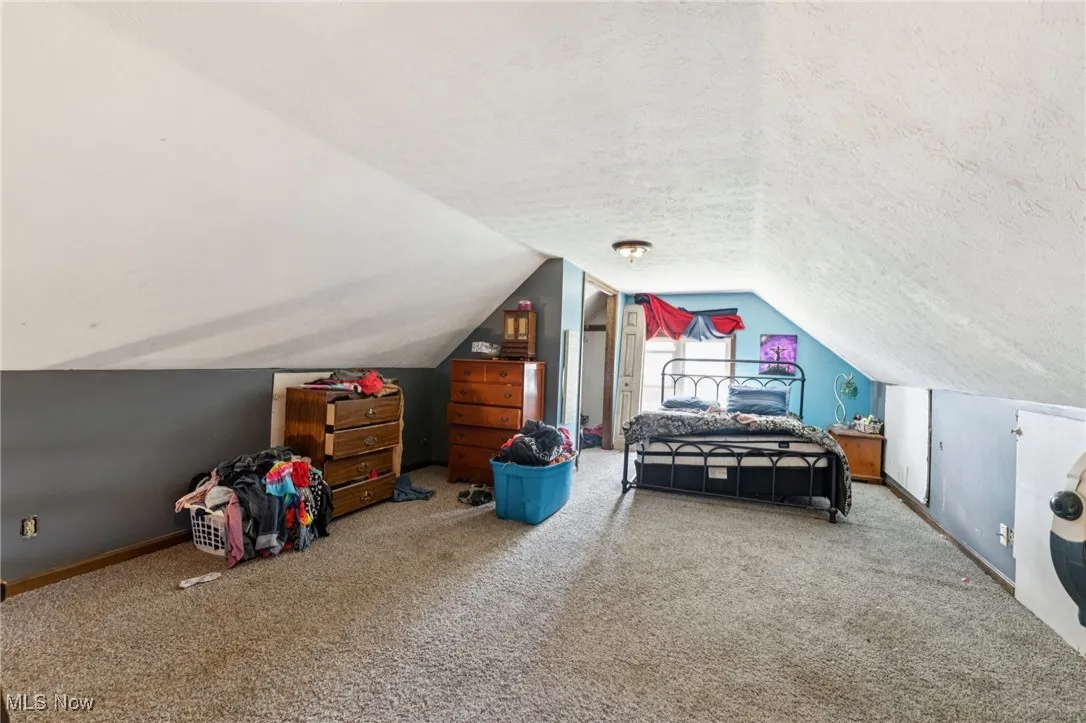 Carpeted bedroom with a textured ceiling and vaulted ceiling