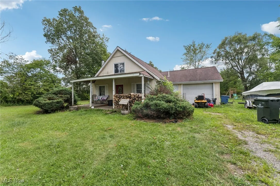 Back of property with a garage, covered porch, and a yard